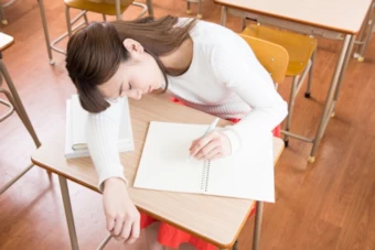 眠そうに学習する女性